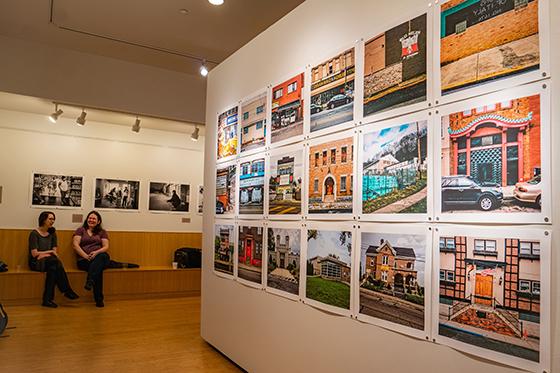 Photo of two women sitting inside the Susan Bergman Gurrentz ’56 Art Gallery surrounded by colorful art prints. 