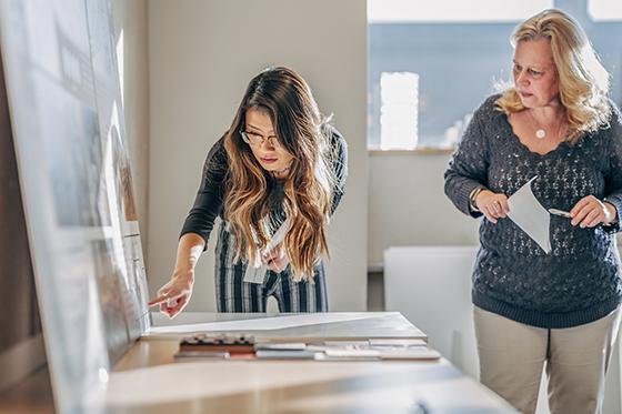 Photo of two women organizing graphics on a poster board