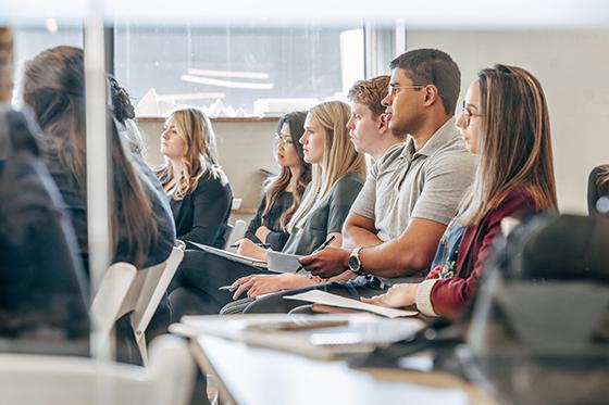 Photo of Chatham University students sitting at desks in a classroom listening to a lecture.