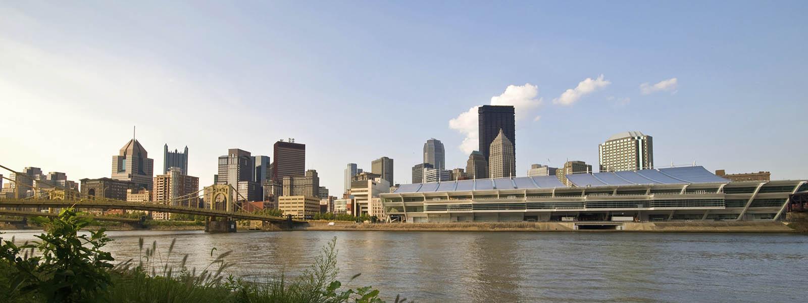 Photo of the Pittsburgh skyline and river with yellow bridges